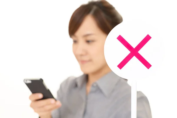 Woman holding smart phone with do not use mobile phone sign