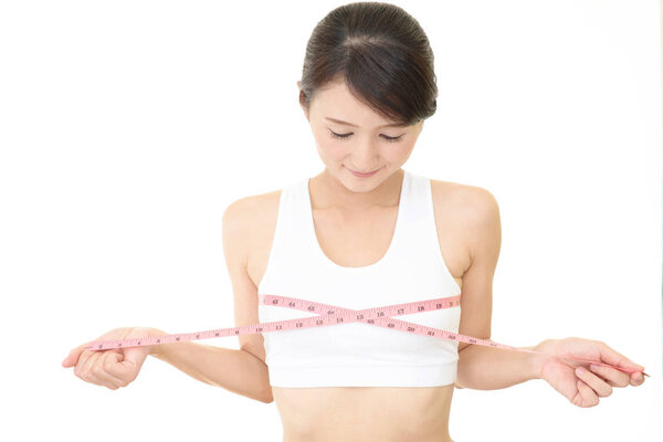 Молодая женщина измеряет свою грудь
