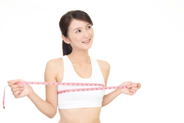 Молодая женщина измеряет свою грудь

