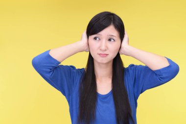 Woman covering her ears isolated on yellow background clipart