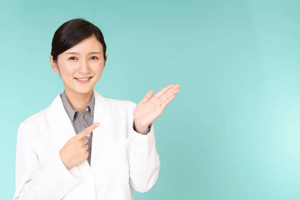 彼女の手の手のひらに何かを示すアジア薬剤師 — ストック写真