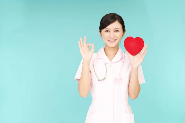 Asyalı Hemşire Kırmızı Kalp Aşk Sembolü Tutan Gülümseyerek — Stok fotoğraf