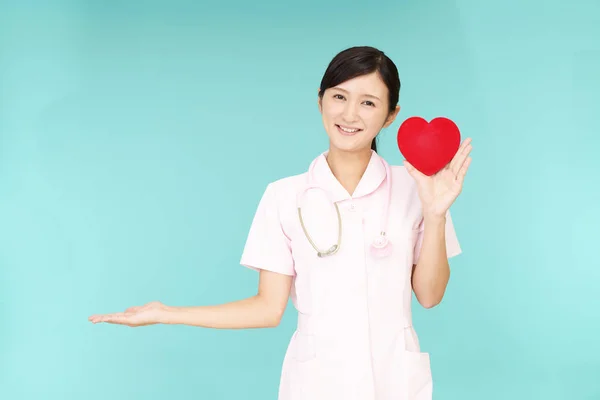 微笑的亚洲护士拿着红心爱的象征 — 图库照片