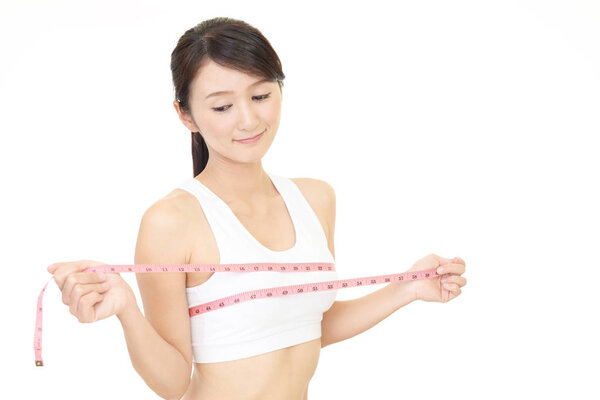 Молодая женщина измеряет свою грудь
