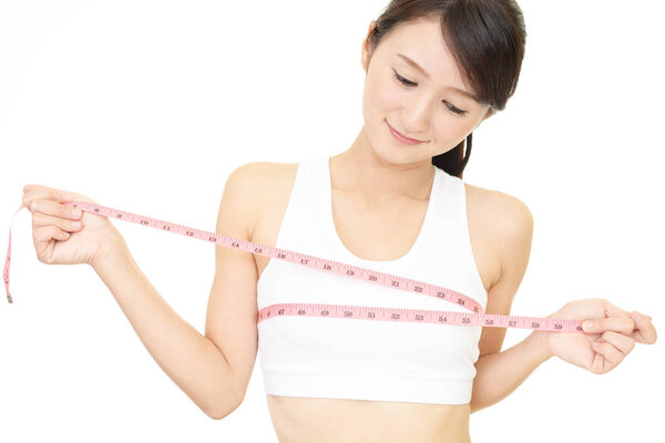 Молодая женщина измеряет свою грудь
