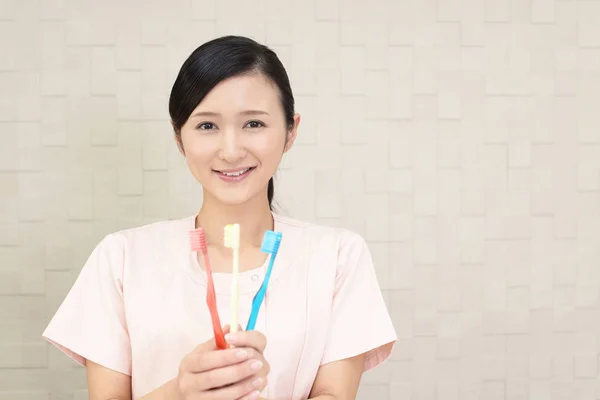 Smiling dental hygienist with toothbrushes