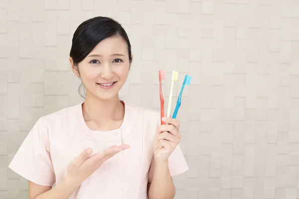 Smiling dental hygienist with toothbrushes