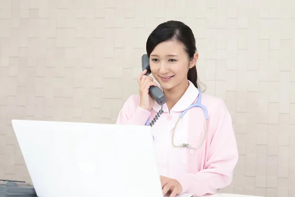 Asian female nurse with a phone