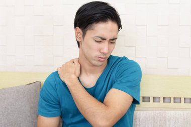 Asyalı bir adam omuz ağrısı çekiyor. 