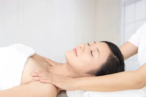 Beautiful woman with closed eyes getting a massage in the spa salon