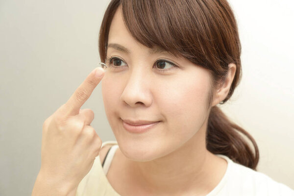 Woman holding contact lens on index finger