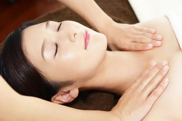 Beautiful woman with closed eyes getting a massage in the spa salon