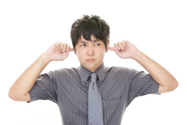 Bir adam kulaklarını tutuyor.