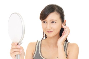 Asyalı kadın aynada yüzüne bakıyor.