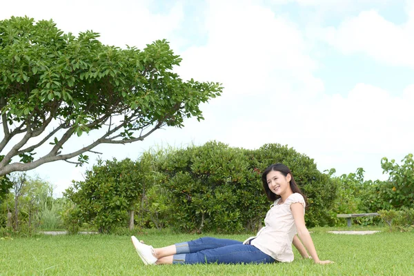 公園でリラックスした若い女性は — ストック写真