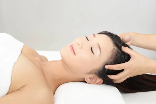 Spa salonundaki kadın kafa masajı yaptırıyor.