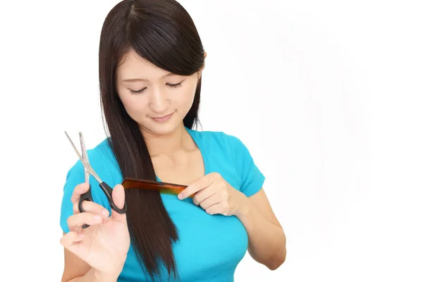 用剪刀剪自己的头发的年轻妇女 — 图库照片