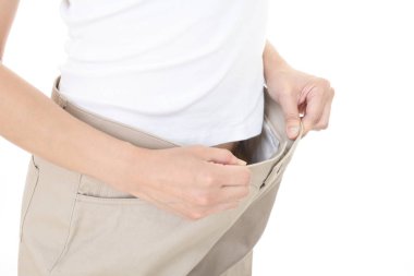 Ayakta ve kilo kaybetme sonra çok büyük pantolon giyen kadın