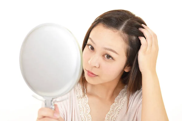 亚洲妇女看着她的头发在手镜 — 图库照片