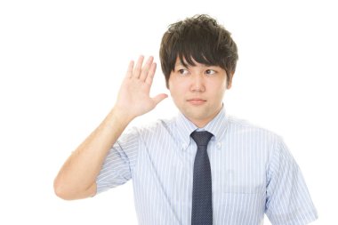 Bir adam elini kulağına koyar.