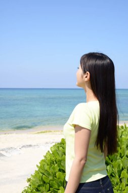 Sahilde genç Asyalı kadın zevk güneş ışığı