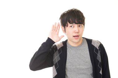 Bir adam elini kulağına koyar.