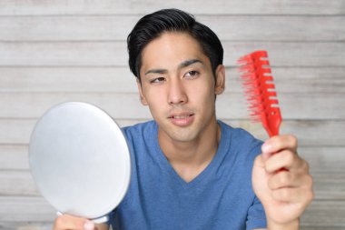 Adam saçlarıyla mutsuz görünüyor.