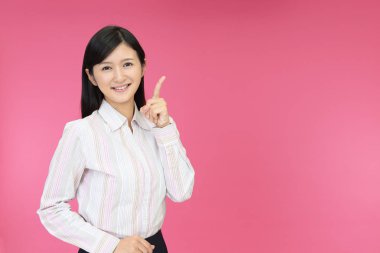 Asyalı genç bir kadın parmağıyla işaret ediyor.