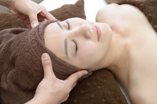 Woman in spa salon receives scalp massage