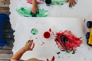 2-3 yıl yaşlı çocuklar çıplak elleriyle beyaz kağıda elleriyle boya onlar yeşil kullanarak, kırmızı ve mavi renk beyaz bez kağıt.