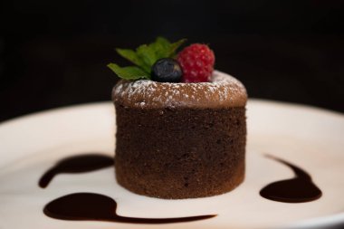 Çikolata erimiş lav kek hazır yemek için. Kırmızı meyve ve ahududu, eritme çikolata eşliğinde. Önden görünüm. Bir tabak içinde hizmet