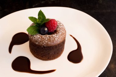 Volkan kek meyve ve pudra şekeri ile dekore edilmiş beyaz bir plaka üzerinde