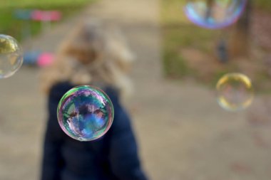 Bir kış günü geriye dönük kız ve arka plan üzerinde patenciler ile yakın sabun köpüğü kadar odaklanmak