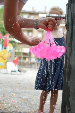 Girld ve pembe Brunch su balon ile yaz saati üzerinde oynarken anne. Park çocuk arka plan