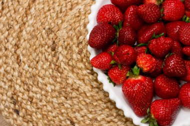 Jüt masa örtüsü üzerinde beyaz tabakta olgun çilek