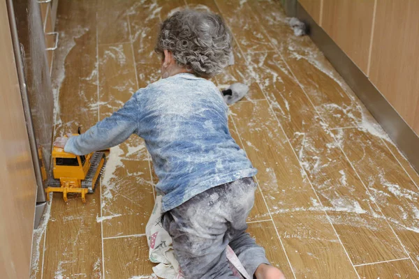 KITCHEN MESSY. LITTLE CHILD PLAYING WITH FLOUR AT THE KITCHEN FL