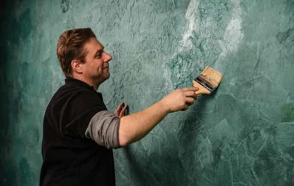 Real professional painter in painting a wall with brush