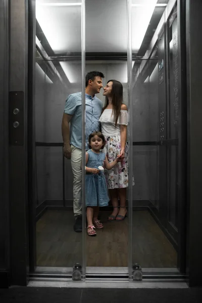 Asansör içinde küçük kızı ile mutlu genç aile. Gülümseyen genç ebeveynler ve çocukları. Sevimli küçük kız ve onun güzel anne. Aile ile küçük kız dinlenme ve sahip olan eğlence