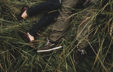 Çimlerin üzerinde yatan mutlu genç bir çift. Yeşil çimenler üzerinde dinlenen bir çift. Romantik kavram. 