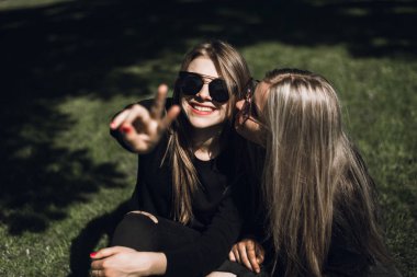 Gülen kızlar eğleniyor ve yeşil çayırda dinlensinler. Komik genç yaz tatili zevk ve yeşil çim üzerinde yalan. Güzel genç kadınlar parkta dışında yaz günlerini harcama
