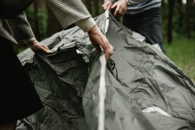 Yaşlı çift tatil zevk ve çadır kuruyor. Yaz tatilini doğada geçiren yetişkinler çadır kurarlar. Yaşlılar kamp ve çadır montaj