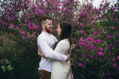 Botanik bahçesinde yürüyen genç bir aile. Parkta yürürken el ele tutuşan sevgi dolu bir çift. Erkek arkadaş ve kız arkadaş bu güzel çiçek bahçesinde nazikçe sarılıyorlar.