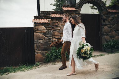 Şık genç çift el ele tutuşuyor ve sokakta yürüyor. Mutlu çift yolda aşık. Şehirde vakit geçiren buketli yakışıklı adam ve güzel bir kadın. Yeni evliler dışarıda eğleniyor. 