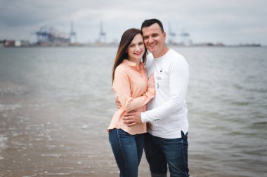 Aşık çift tatil zevk ve deniz kenarında eğlenmek. Genç mutlu aile sahilde yürüyor. Erkek ve kadın kucaklıyor ve el ele tutuşuyor. Aşıklar kumda yürür. Romantik kavram