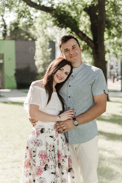 Young couple on the street in summer. Man and woman in love having a walk outdoors. Beautiful pair hugging and looking at each other in European city. Dating concept. Love story