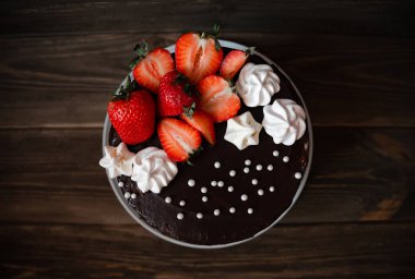 Çilek, beze ve inci ile Çikolatalı kek. Ahşap masada en iyi manzara lezzetli çikolatalı turta. Üstüne bir dekorasyon ile tatlı lezzetli bisküvi. Closeup