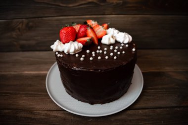 Çilek, beze ve inci ile Çikolatalı kek. Ahşap masada en iyi manzara lezzetli çikolatalı turta. Üstüne bir dekorasyon ile tatlı lezzetli bisküvi. Closeup
