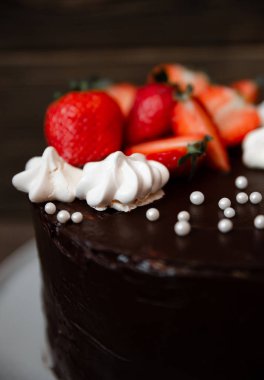 Çilek, beze ve inci ile Çikolatalı kek. Ahşap masada en iyi manzara lezzetli çikolatalı turta. Üstüne bir dekorasyon ile tatlı lezzetli bisküvi. Closeup