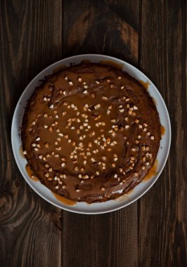 Fındıklı çikolatalı kek. Ahşap masada lezzetli koyu çikolatalı kek görünümü. Bir bisküvi kek çikolata krema ile ceviz serpilir. Closeup