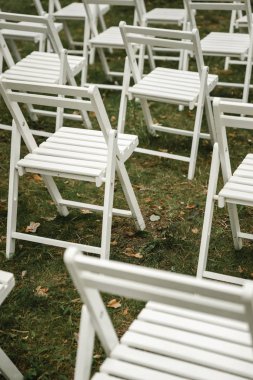 Çimlerin üzerinde duran düğün sandalyeleri. Beyaz